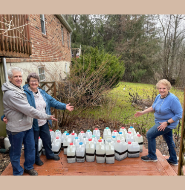 People standing next to several seed sowing plastic jugs